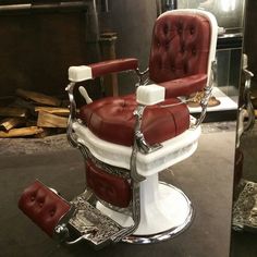 a red and white barber chair sitting on top of a table next to a mirror