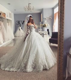 a woman in a wedding dress taking a selfie with her cell phone while standing in front of a mirror