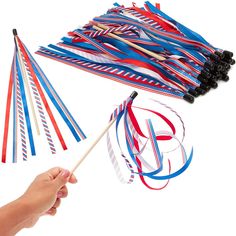 a hand holding a toothpick and some colorful streamers on a white background