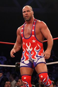 a wrestler standing in the ring with his hands on his hips