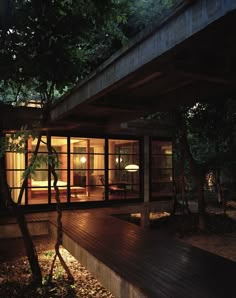 a house that is lit up at night with lights on the windows and wood flooring