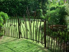 an iron fence in the middle of a lush green yard