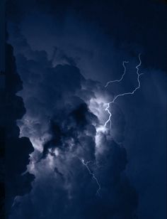 the sky is filled with clouds and lightnings as it breaks through dark blue hues