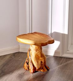 a wooden stool sitting on top of a hard wood floor next to a white wall