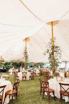 an outdoor tent with tables and chairs set up for a formal dinner or party in the grass