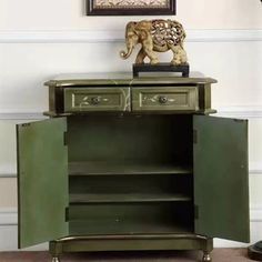 an elephant statue on top of a green cabinet