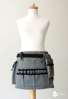 a white mannequin wearing a gray skirt with pockets on the front and side