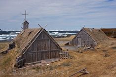 two old wooden buildings with thatched roofs near the ocean