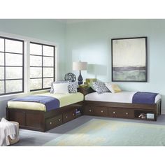 two twin beds in a room with blue walls and white carpeted flooring, framed pictures on the wall above them