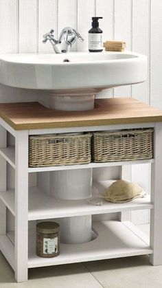 a white sink sitting under a bathroom mirror next to a wooden shelf with baskets on it