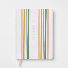 a white notebook with multicolored stripes and the word journal written in gold foil