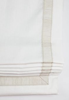 the white sheets are folded neatly on top of each other, with an embroidered border