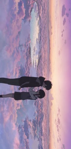 two people standing in front of the ocean with their arms around each other and looking at the sky