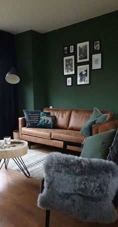 a living room with dark green walls and leather couches, coffee table, and pictures on the wall