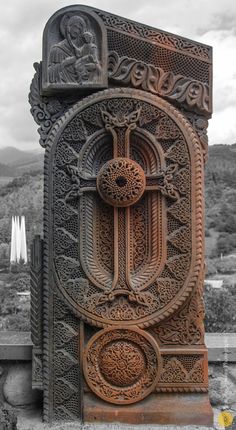 an intricately carved door on the side of a building with mountains in the background