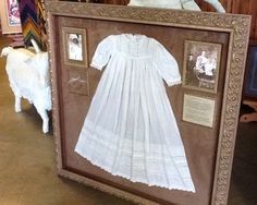 a framed photo of a baby's christ gown with pictures on the front and back