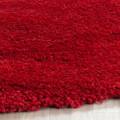 a red rug is on the floor in front of a white wall and wooden floors