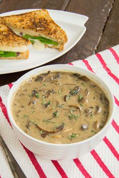 a bowl of soup and a plate with a sandwich on it sitting on a table