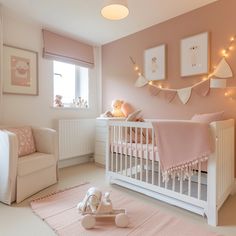 a baby's room with pink walls and white furniture