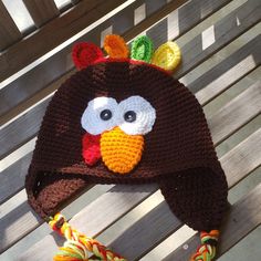 a crocheted turkey hat sitting on top of a wooden bench