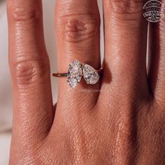 a woman's hand with an engagement ring on top of her finger, and the other half of her wedding band