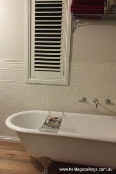 a white bath tub sitting in a bathroom next to a window with blinds on it