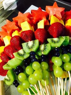 fruit skewers are arranged on sticks with grapes, kiwis and strawberries