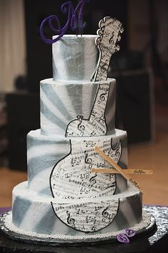 a three tiered cake decorated with music notes and a guitar on the bottom layer