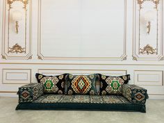 a couch sitting in front of a white wall with ornate designs on the back and sides