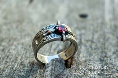 a close up of a ring with a red stone in it on a wooden surface