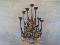 a metal sculpture sitting on top of a wicker table next to a cement wall