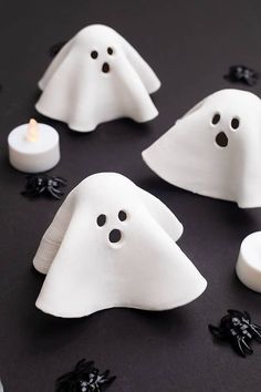 some white ghost candles are on a black table