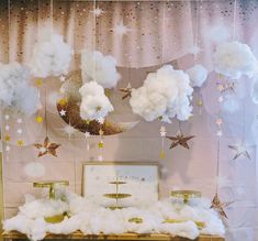 clouds and stars hanging from the ceiling in front of a table with decorations on it