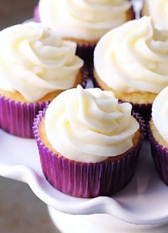 cupcakes with white frosting sitting on a plate