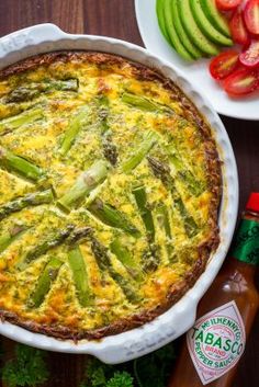 a quiche with asparagus and tomatoes on a table next to ketchup