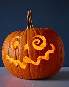 a carved pumpkin with an evil face on it's side, sitting on a table