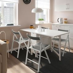 a kitchen table with chairs and a clock on the wall