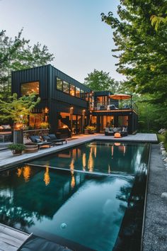 a house with a pool in front of it surrounded by trees and grass, at dusk