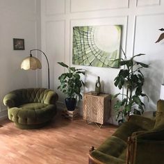 a living room with two green chairs and a painting on the wall above it's windows