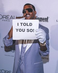 a man in a suit and sunglasses holding up a sign that says i told you so