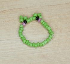 a green beaded bracelet sitting on top of a wooden table