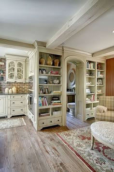 a living room filled with lots of furniture and bookshelves next to a window