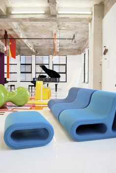 an office with colorful chairs and piano in the back drop off area, while another chair sits on the floor next to it