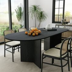 a dining table with chairs around it and fruit on the table in front of large windows