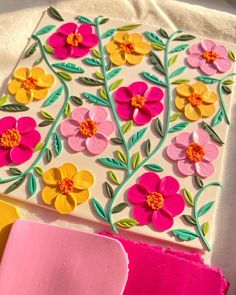 some paper flowers are sitting on top of a piece of pink and yellow material with green leaves