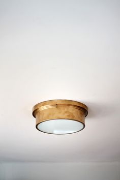 a light that is on the side of a wall mounted ceiling fixture with a circular glass shade