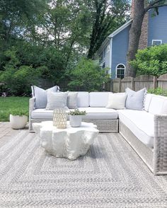 a couch and table on a patio with trees in the background