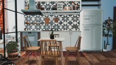 a kitchen with a table and chairs in front of a refrigerator freezer next to a potted plant