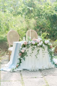 a table with flowers and candles is set up for an outdoor wedding reception in the woods