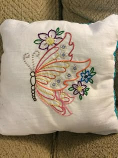 a white pillow with a butterfly embroidered on the front and back, sitting on a couch